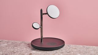 The Anker MagGo Charging Station 3-in-1 stand sits facing slightly to the right. It is sitting on a stone-effect surface with a pink background.