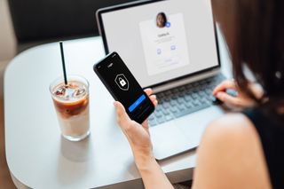 Person holding a locked smartphone and using a laptop