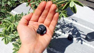 one nuratrue earbud on an open palm, showing the inside of the earbud