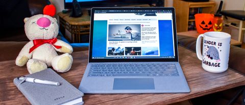 Microsoft Surface Laptop 4 on a coffee table next to a notebook and a coffee cup