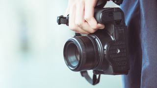 A hand holding a DSLR camera