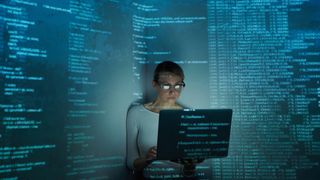 Confident young woman using computer against dark background