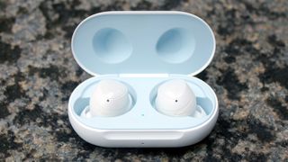 A pair of Samsung Galaxy Buds in white in their charging case on a grey surface