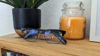 The Lucyd Lyte glasses next to a plant and a yellow candle sat on a bookshelf