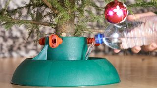 Man pouring water from a plastic bottle into a Christmas tree stand