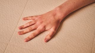 A close-up of a hand feeling the materials of the Nolah Natural 11 Mattress 's cover design