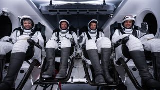 The four astronauts of SpaceX's Polaris Dawn private mission pose in black and white spacesuits inside their Dragon capsule.