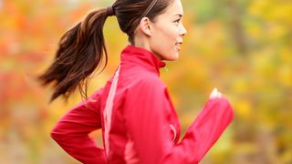 Happy woman in pink jacket running in the woods