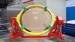 an orange frame holds a large mirror supported by a yellow ring structure.