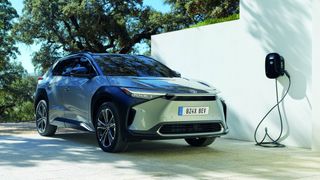 Toyota bZ4X parked in a driveway next to an electric car charger