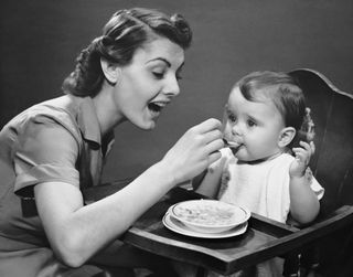 1950s mom feeding her baby.