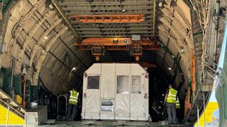 a large white boxy object sits in the cargo bay of a plane