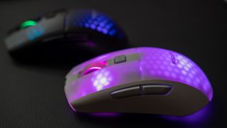 Två stycken Roccat Burst Pro Air ligger mot en mörk yta med RGB-belysningen aktiv