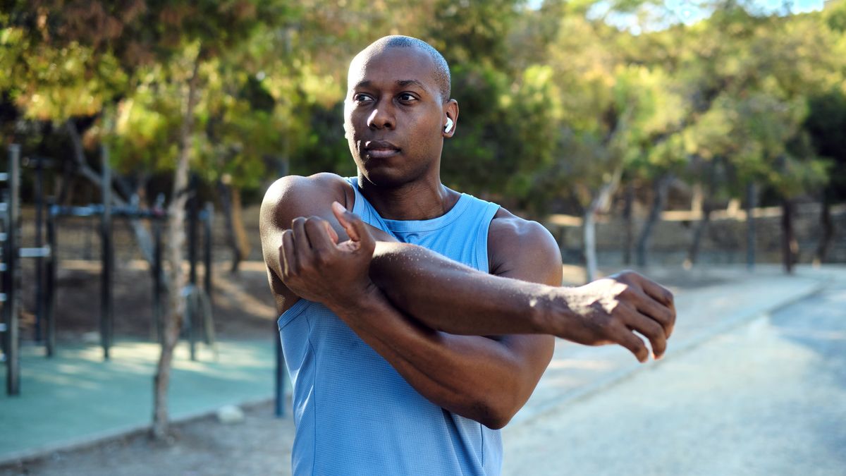 Man stretching before a workout outside while listening to music