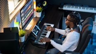 A person composing with a synth at a PC.