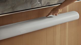 Sonos Arc Ultra in white with a woman's hand pressing the control