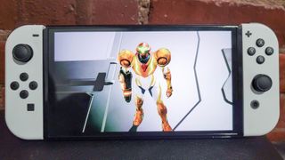 Best Handheld Gaming Devices 2024 - Nintendo Switch OLED on top of a deck with Samus looking up towards the screen in a Metroid Dread cutscene.