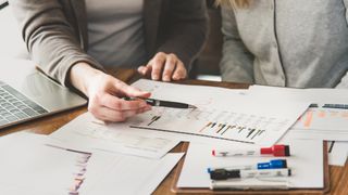 Two female employees examining and analysing the growth rate of investment.