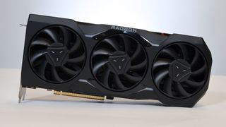 Et skjermkort av typen AMD Radeon RX 7900 XTX liggende på et bord, sett mot en lys bakgrunn.