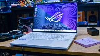 Bästa gaminglaptop: En Asus ROG Zephyrus G14 står öppnad på ett bord i ett rum fyllt med teknikprylar.