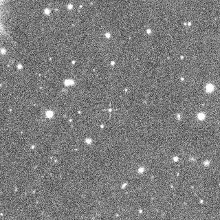 black and white, grainy image of deep space, showing several dozen fuzzy points of light