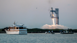 A giant SpaceX rocket hovers near a lauch tower with metal arms trying to catch it as people watch from boats