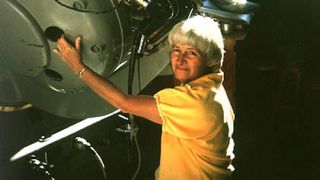 Carolyn Shoemaker wearing a yellow shirt and smiling at the camera.