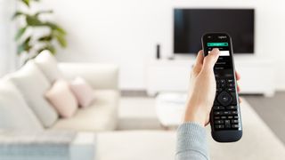 Someone holding a universal remote in a white living room