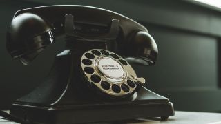 Black Rotary Telephone on White Surface