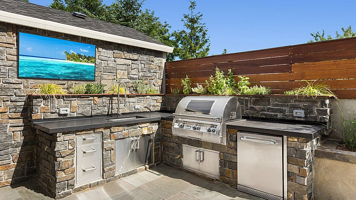 A TV hangs in an outdoor BBQ area