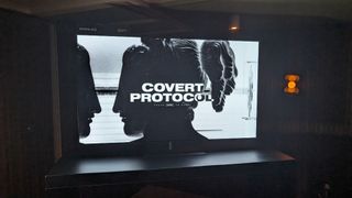 A photograph of a large TV displaying the Nvidia ACE 'Covert Protocol' demo.