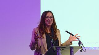 Tricia Troth, general manager at AWS Startup for the UK & Ireland, speaking onstage at the AWS Loft in London. Decorative: Troth is stood at a podium, with a purple and white backdrop.