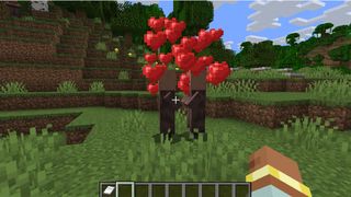 Two villagers in Minecraft about to breed with heart icons floating above their head.