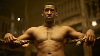 Malachi Kirby with his shirt off leaning against the ropes of a boxing ring