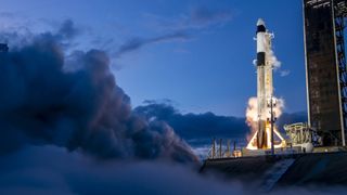 A white and black SpaceX Falcon 9 rocket test fires its engines on the launch pad for Polaris Dawn.