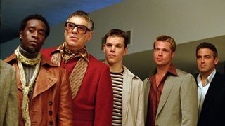 Nogle af hovedpersonerne i røverbanden i Ocean's Eleven. De er velklædte og kigger på noget uden for kameraet.