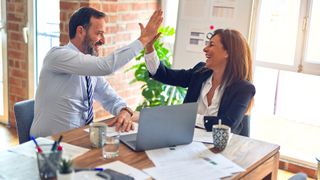 Two people high fiving in a business meeting.