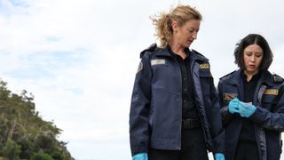 Dulcie and Abby wearing blue gloves investigating a crime on the beach.