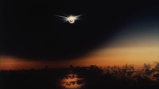 A solar eclipse over the Pacific Ocean at sunset, with the &quot;diamond ring&quot; feature visible.