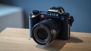 Leica SL3 camera on a wooden surface against a blue background