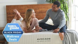 A couple sitting on an Avocado mattress with a Tom's Guide Black Friday label