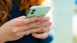 close up on a young woman's hands as she's holding a phone with its screen away from the camera