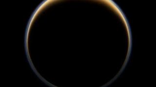 A dark sphere bounded by a brown-yellow ring that is thicker at the sphere's north pole