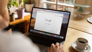 A person sitting in front of a laptop showing a Google search page