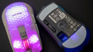 Två stycken Roccat Burst Pro Air ligger upp- och nedvända mot en mörk yta med RGB-belysningen aktiv