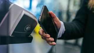 Woman using her iphone to make a contactless payment