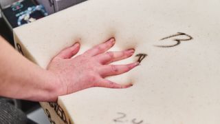 A tester's hand on a piece of memory foam at the 3Z Brands factory in Arizona