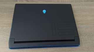 Alienware M15 R7 ligger stängd på ett ljust träfärgat skrivbord.