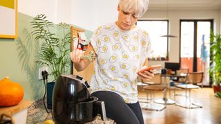 Woman setting up air fryer using phone