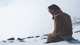 ENZO VOGRINCIC as NUMA looking helpless and kneeling in the snow.